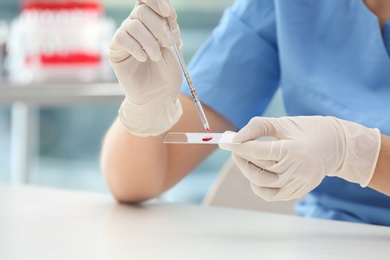 Scientist dripping blood sample on glass in laboratory