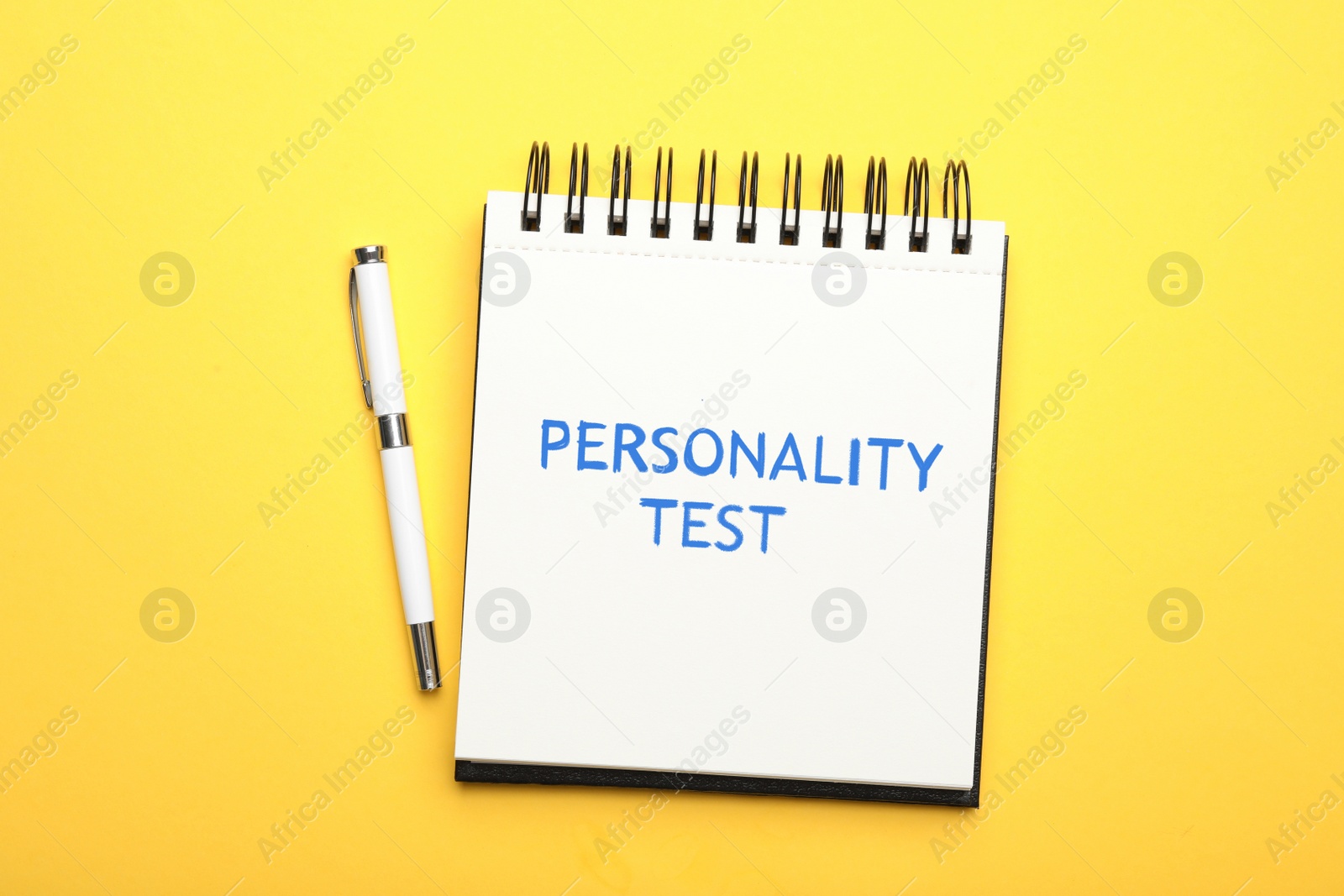 Image of Notebook with text Personality Test and pen on yellow background, top view