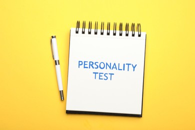 Notebook with text Personality Test and pen on yellow background, top view