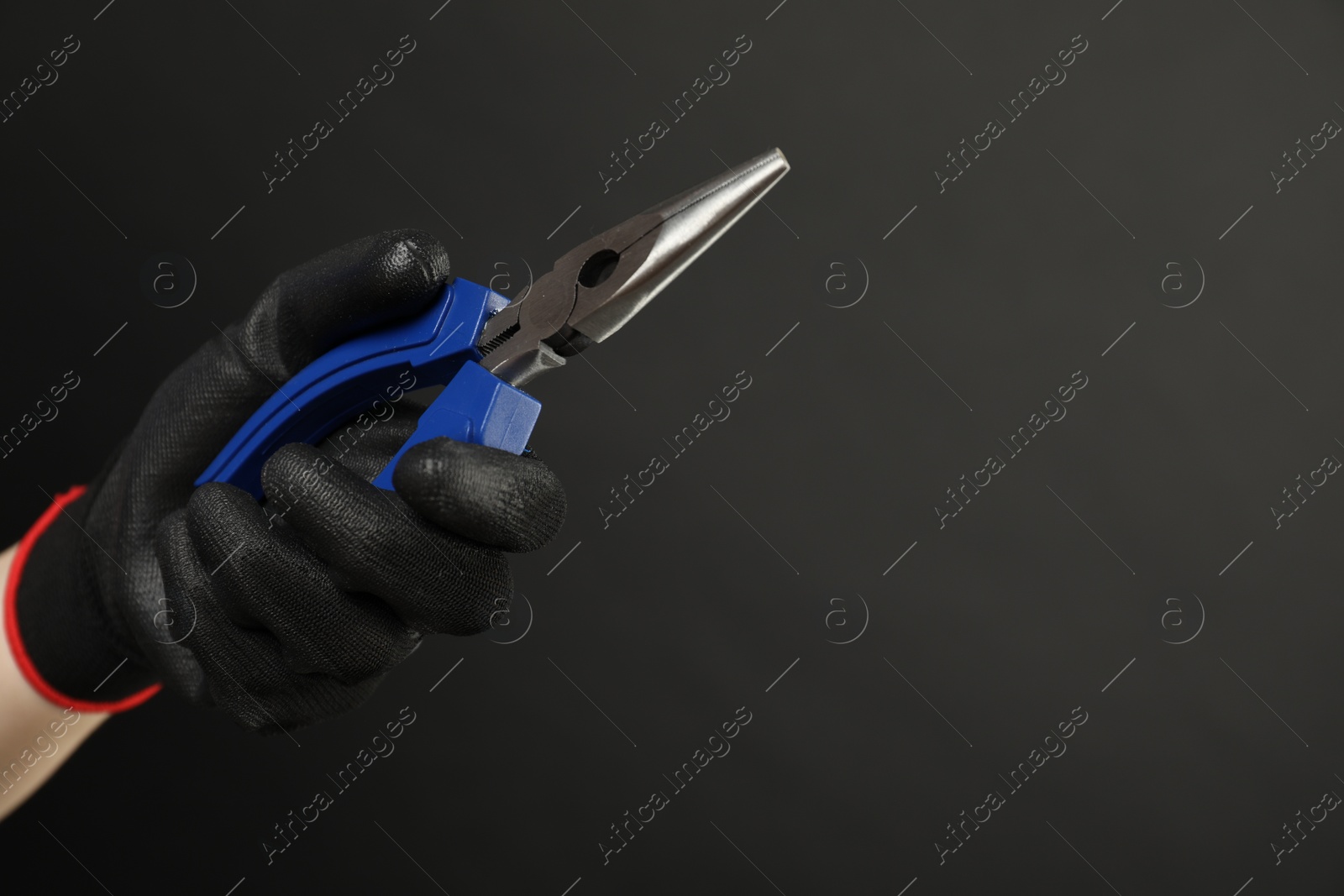 Photo of Woman with needle nose pliers on dark background, closeup. Space for text