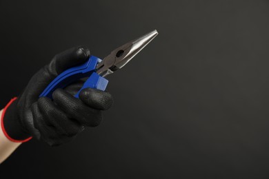 Photo of Woman with needle nose pliers on dark background, closeup. Space for text