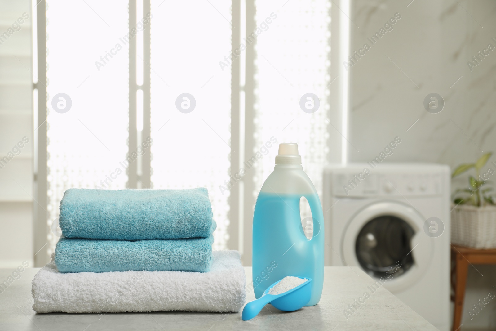 Photo of Clean towels and detergents on table in laundry room