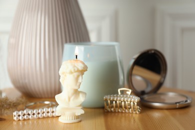 Photo of David bust candle on wooden table. Stylish decor