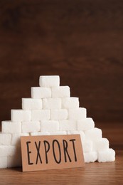 Photo of Card with word Export near pyramid of sugar cubes on wooden table, space for text