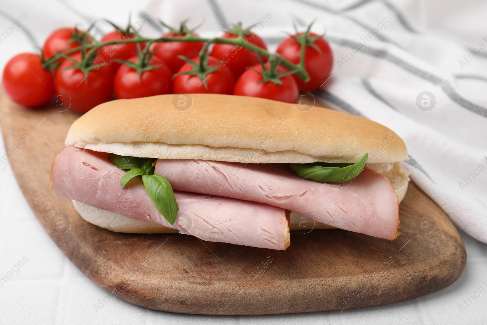 Photo of Delicious sandwich with ham and basil on white table, closeup