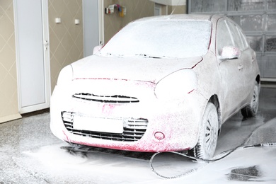 Photo of Auto covered with foam at car wash. Cleaning service