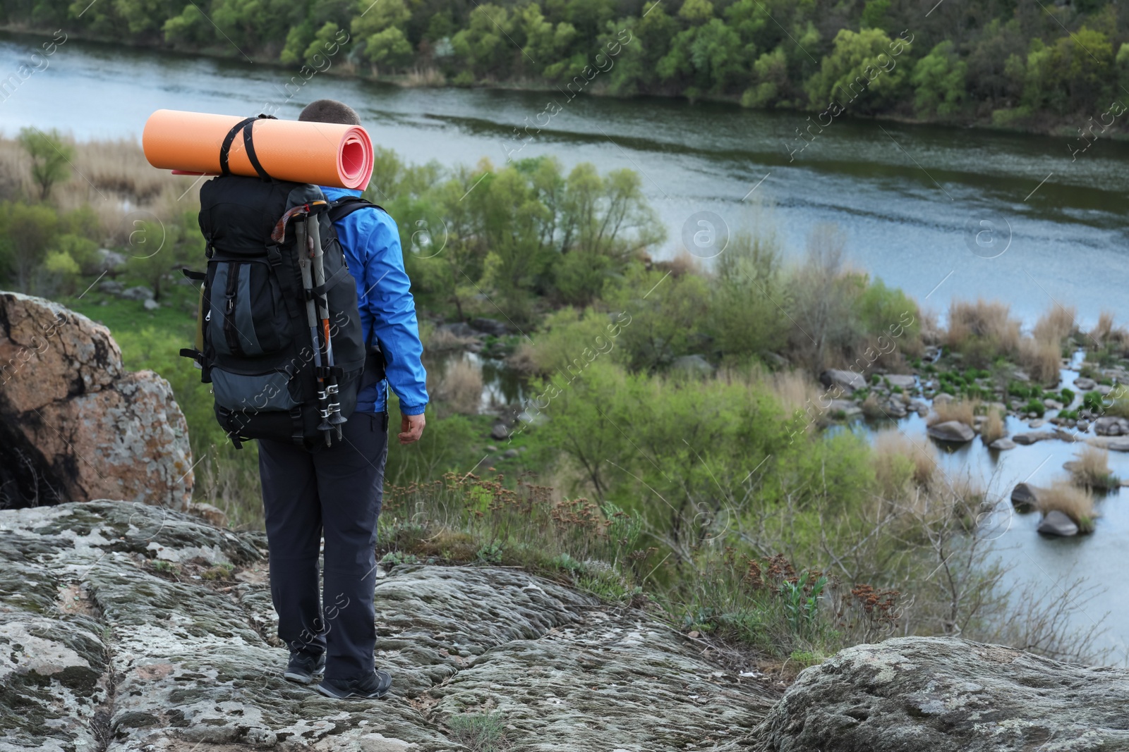 Photo of Hiker with backpack ready for journey on rocky hill, back view