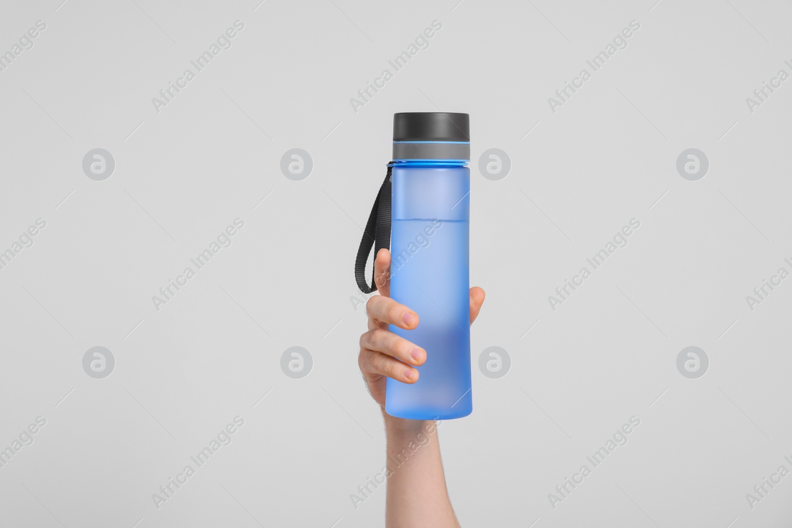 Photo of Man holding transparent plastic bottle with drink on light grey background, closeup