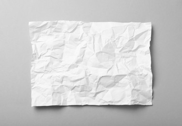 Photo of Sheet of white crumpled paper on grey background, top view