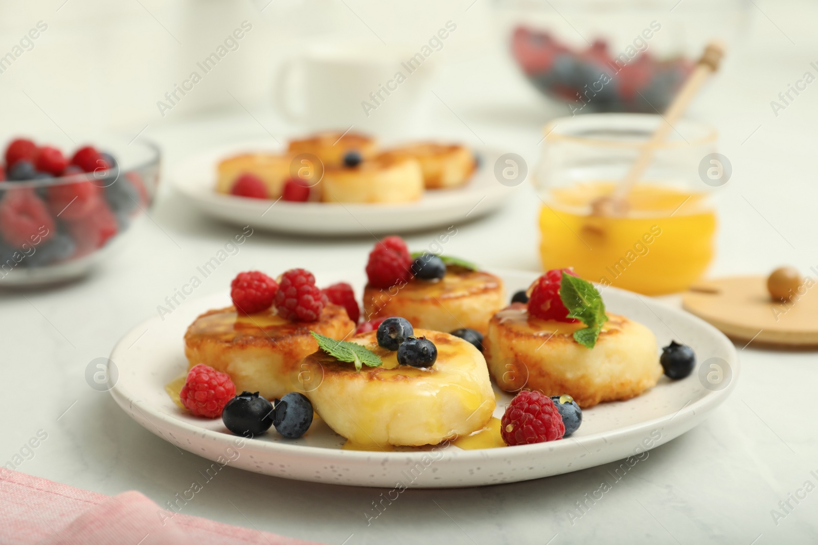 Photo of Delicious cottage cheese pancakes with fresh berries and mint on white table