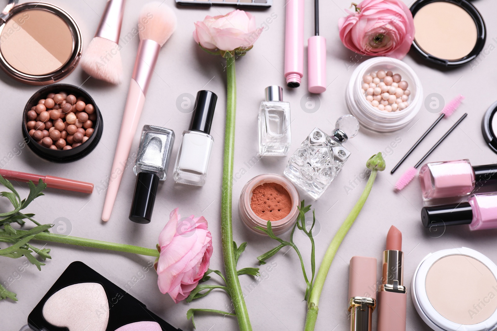 Photo of Flat lay composition with different makeup products and beautiful spring flowers on gray background