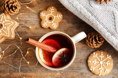 Photo of Flat lay composition with cup of hot winter drink, Christmas lights and cookies on wooden background. Cozy season