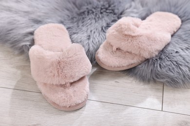 Pink soft slippers on light wooden floor at home, closeup