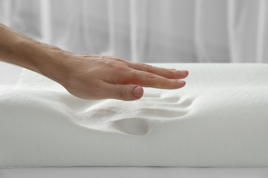 Photo of Man with orthopedic memory foam pillow indoors, closeup