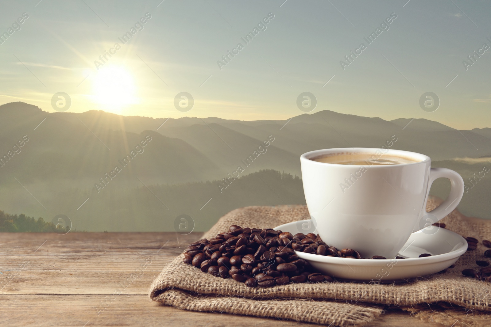 Image of Cup of aromatic hot coffee on wooden table and beautiful view of mountain landscape. Space for text