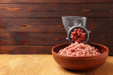 Photo of Manual meat grinder with beef mince on wooden table, space for text