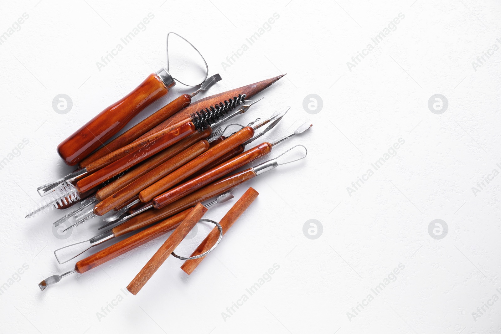 Photo of Set of different clay crafting tools on white textured table, flat lay. Space for text