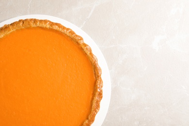 Photo of Fresh delicious homemade pumpkin pie on light background, top view. Space for text