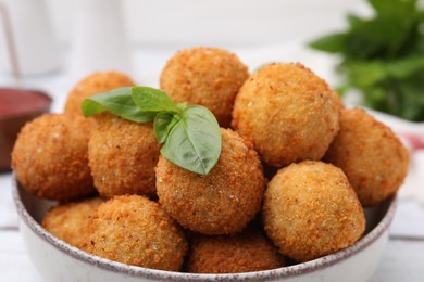 Photo of Bowl of delicious fried tofu balls with basil, closeup