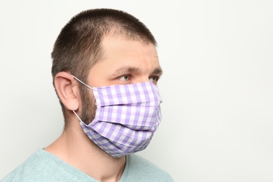 Photo of Man wearing handmade cloth mask on white background, space for text. Personal protective equipment during COVID-19 pandemic