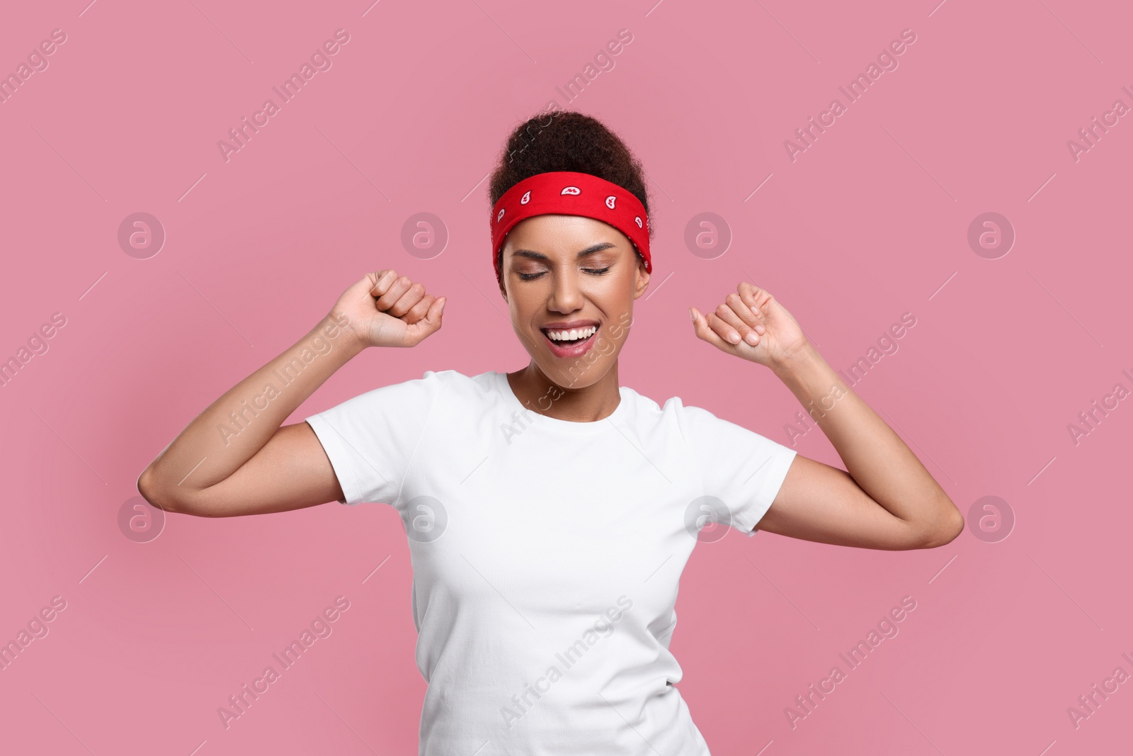 Photo of Happy young woman in stylish headband dancing on pink background