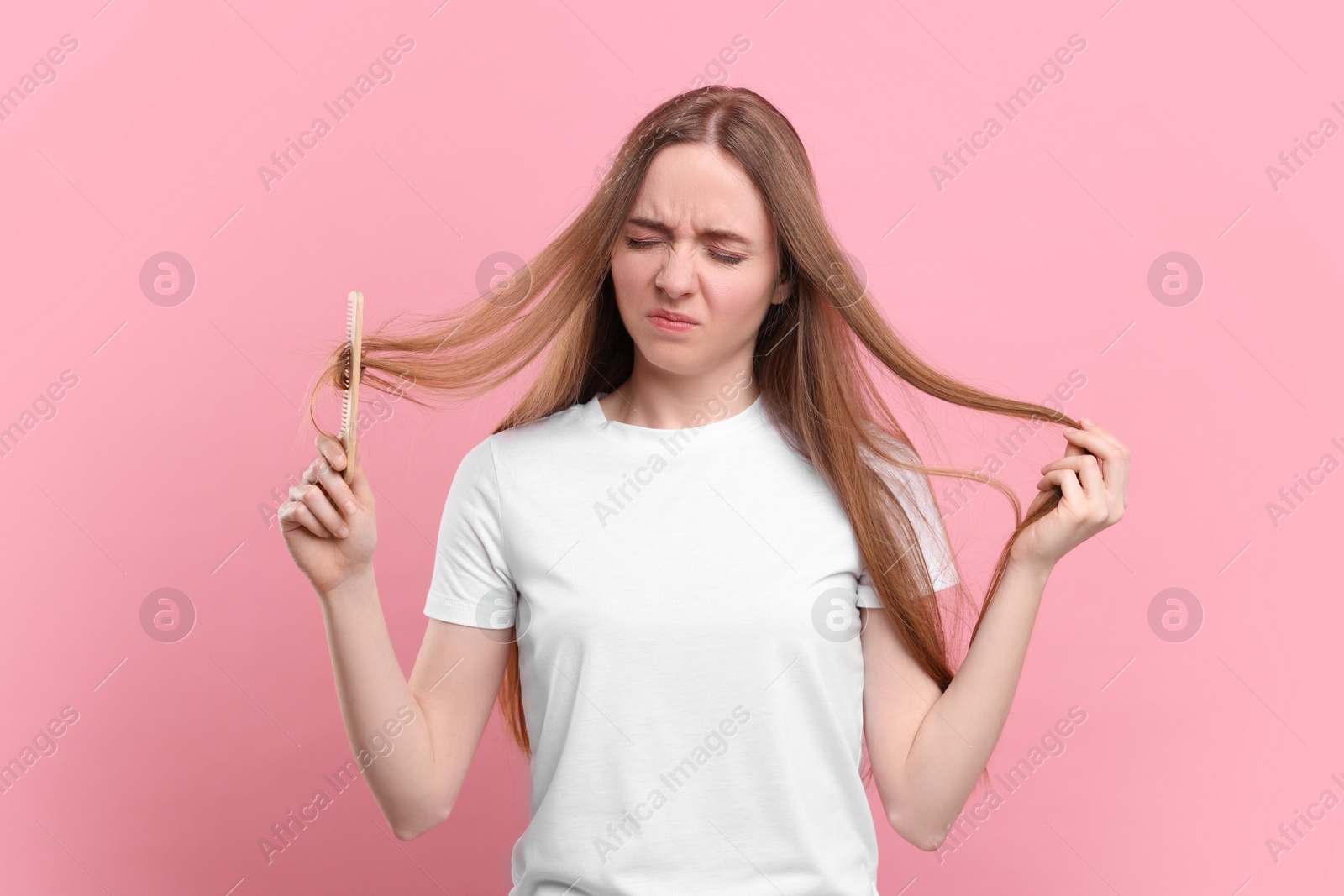 Photo of Emotional woman brushing her hair on pink background. Alopecia problem