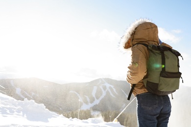 Photo of Woman with backpack enjoying mountain view during winter vacation. Space for text