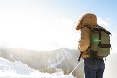 Woman with backpack enjoying mountain view during winter vacation. Space for text