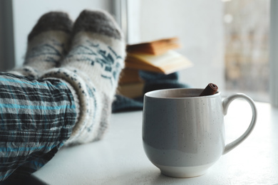 Photo of Woman and cup of mulled wine near window indoors, closeup. Winter drink