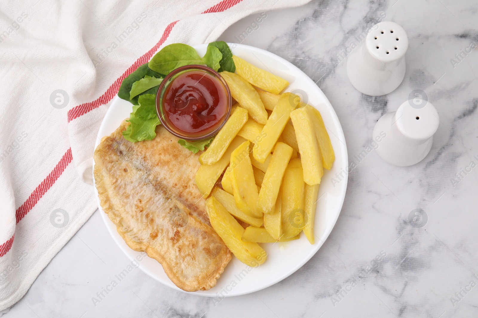 Photo of Delicious fish and chips with ketchup, spinach and lettuce on light marble table, flat lay