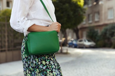 Photo of Woman with stylish green bag on city street, closeup. Space for text