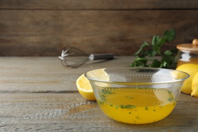 Bowl with lemon sauce on wooden table, space for text. Delicious salad dressing