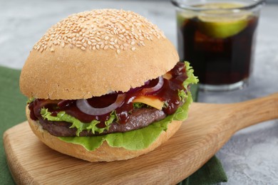 Photo of Board with delicious cheeseburger on table, closeup