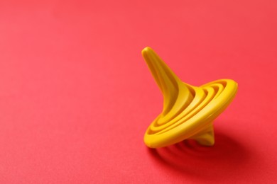 Photo of One yellow spinning top on red background, closeup. Space for text