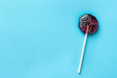 Photo of Sweet colorful lollipop with berries on light blue background, top view. Space for text