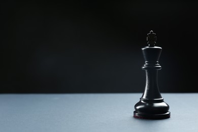 Photo of Black king on table against dark background, space for text. Chess piece