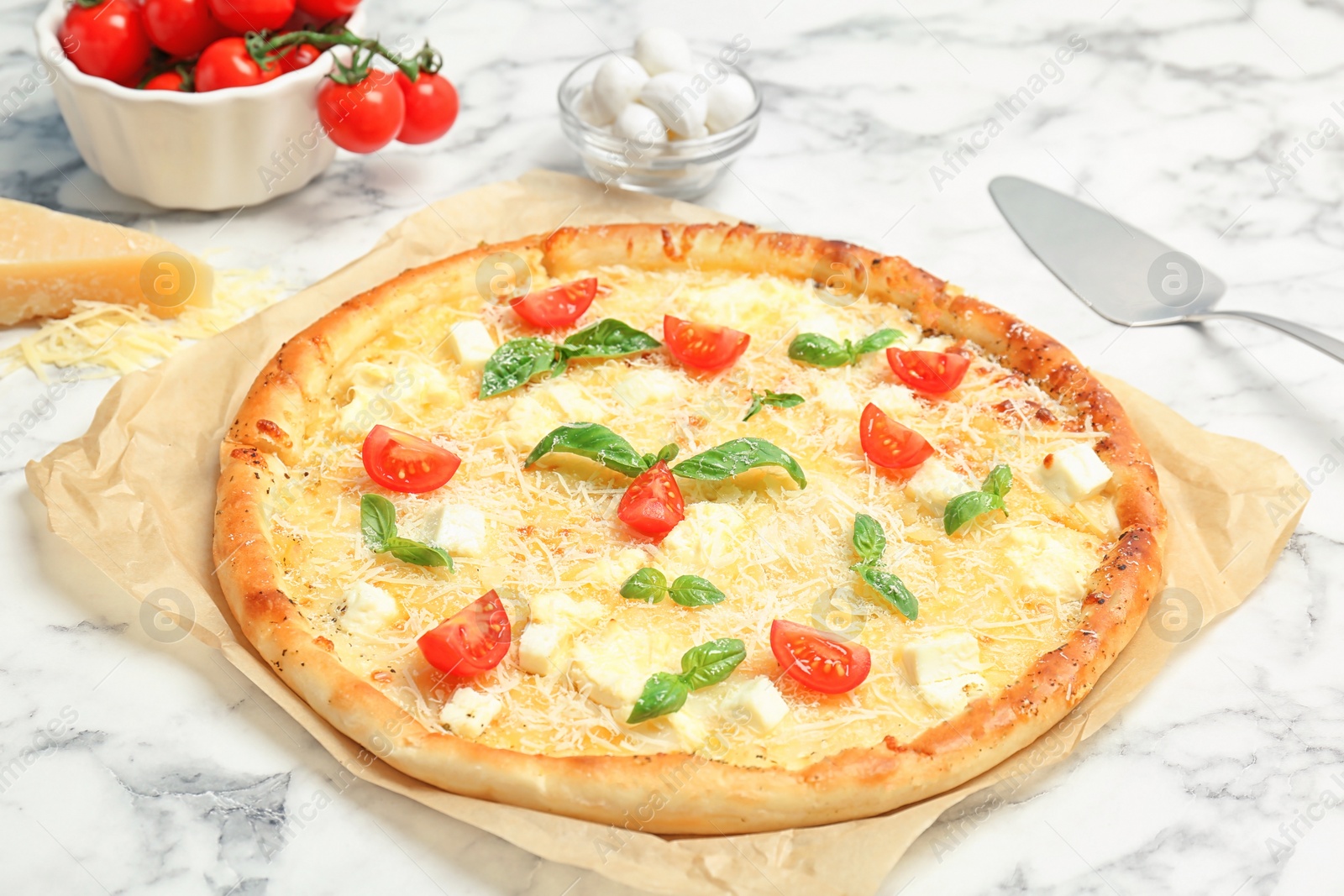 Photo of Delicious pizza with cheese, basil and tomatoes on marble table