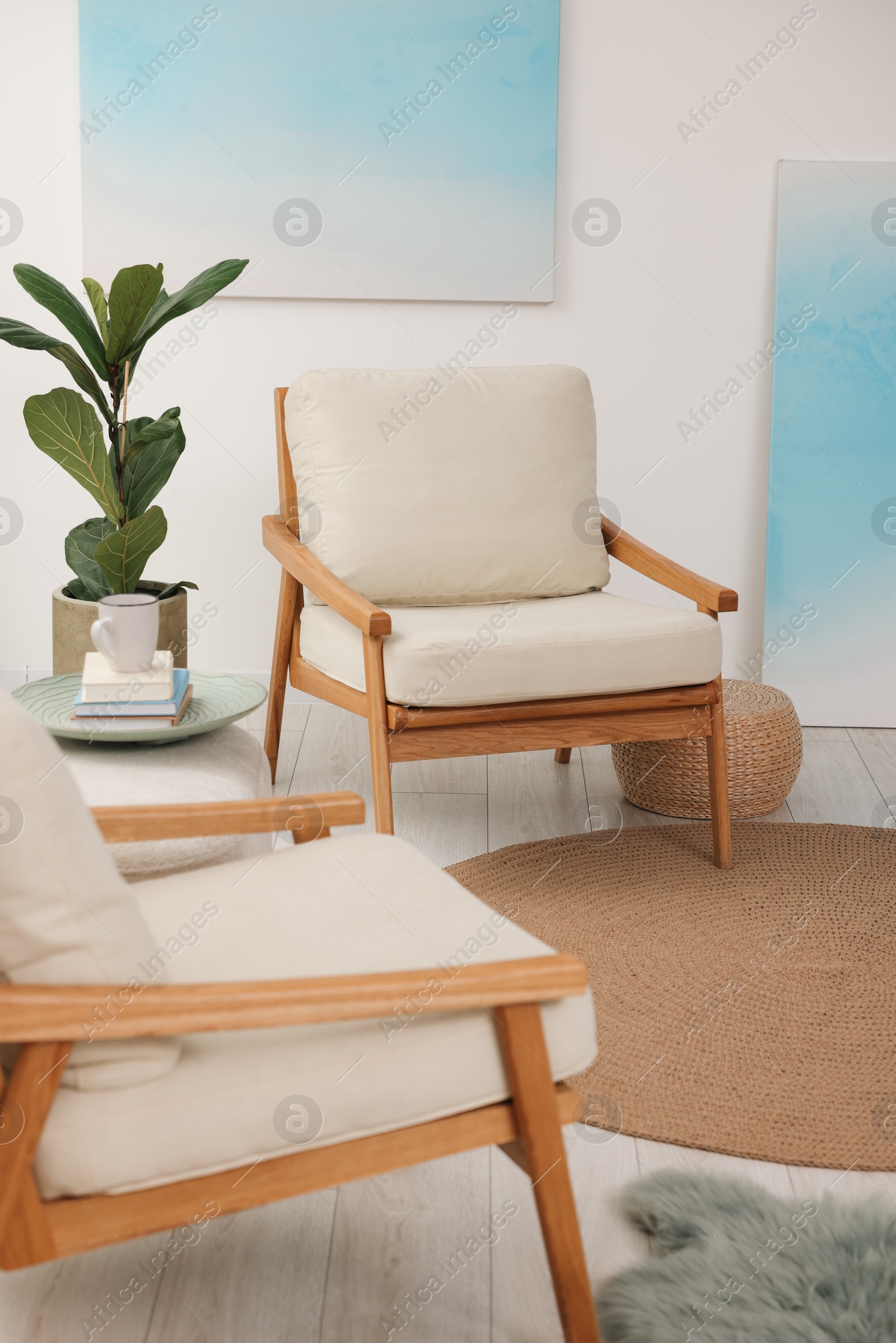 Photo of Comfortable beige armchairs, ottoman and houseplant in living room. Interior design
