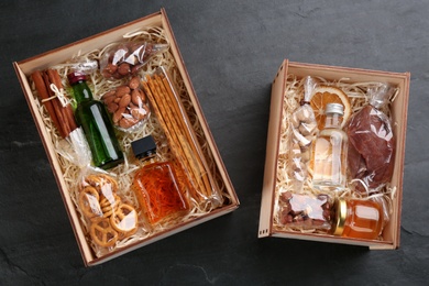 Photo of Boxes with stylish craft gift sets on black slate table, flat lay