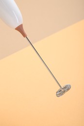 White milk frother wand on color background, closeup