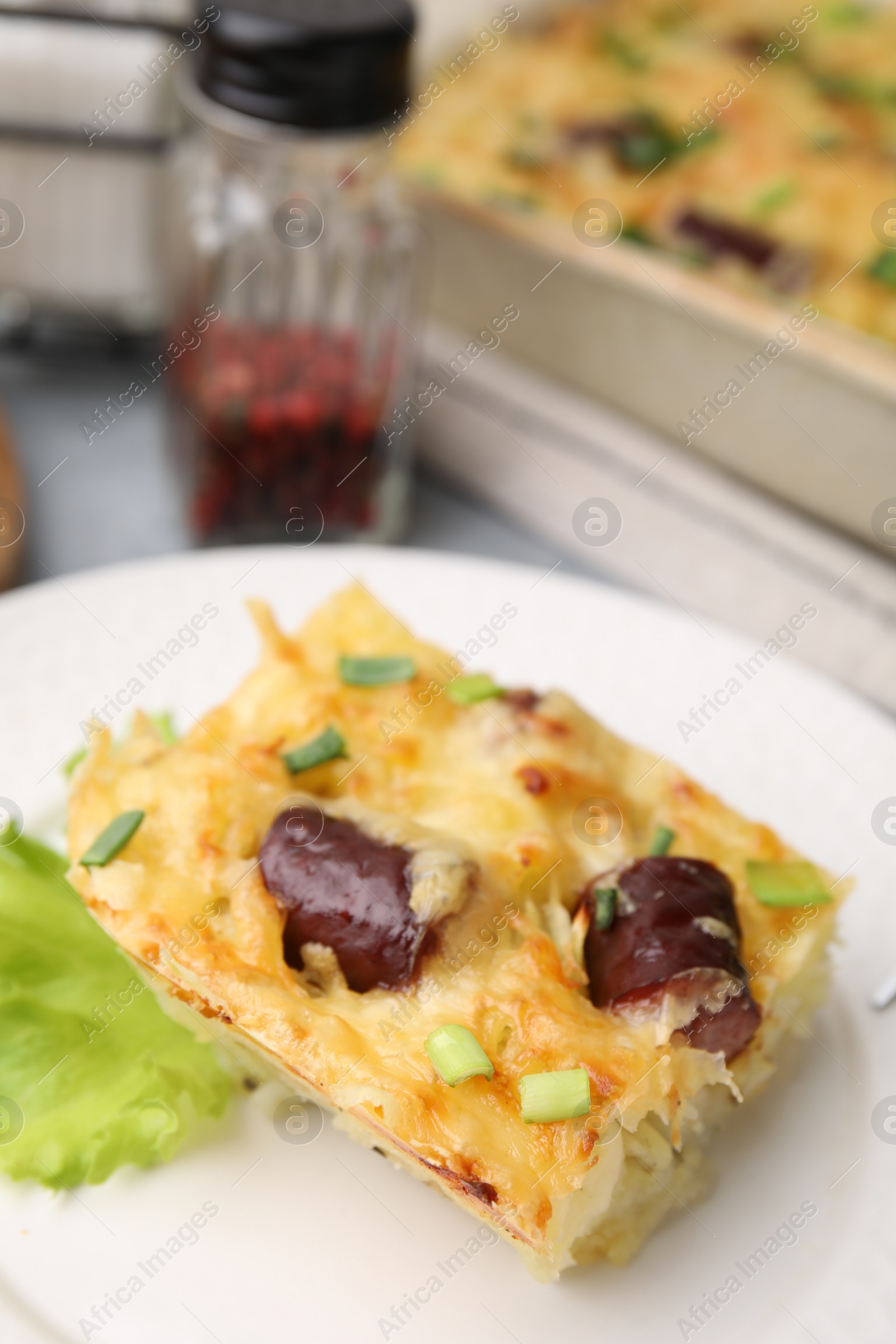 Photo of Tasty sausage casserole with green onions served on table, closeup