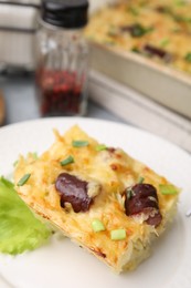 Photo of Tasty sausage casserole with green onions served on table, closeup