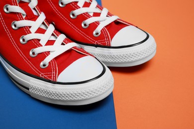 Pair of new stylish red sneakers on colorful background, closeup