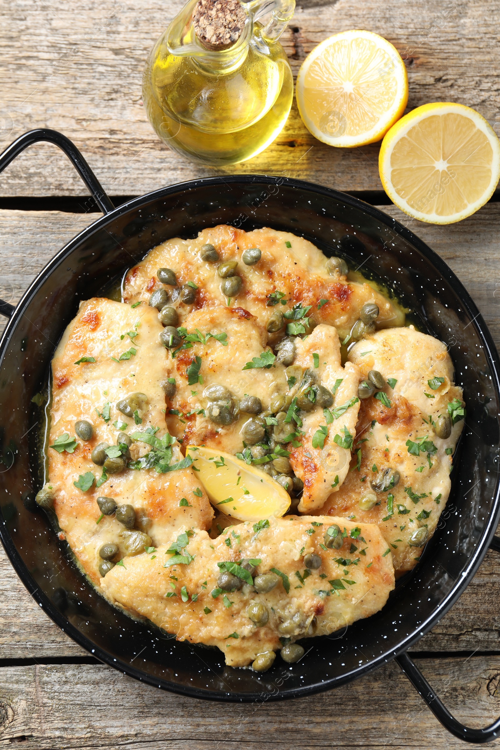 Photo of Delicious chicken piccata with herbs and lemon on wooden table, flat lay