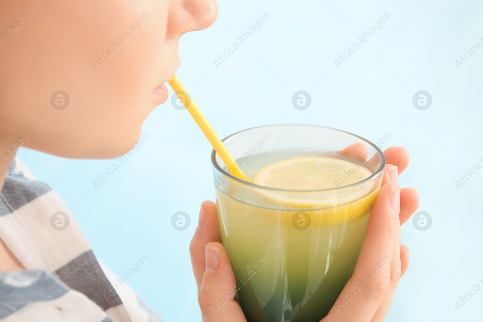 Photo of Young woman drinking lemon cocktail against color background