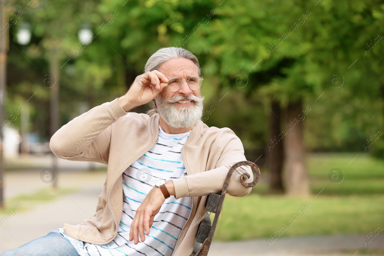 Photo of Handsome mature man sitting on bench in green park