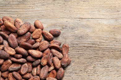 Photo of Tasty cocoa beans on wooden table, top view. Space for text