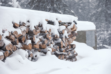 Photo of Stack of firewood covered with snow outdoors