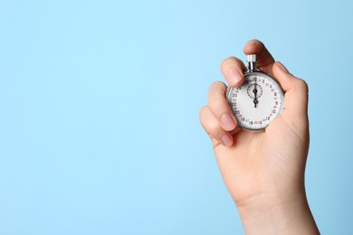 Photo of Woman holding vintage timer on light blue background, closeup. Space for text