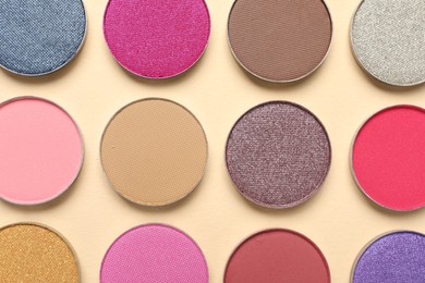 Photo of Different beautiful eye shadows on beige background, flat lay